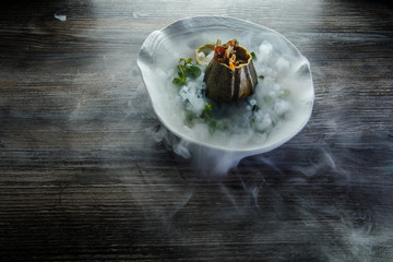 top view on dessert served in pumpkin decorated with mint and smoke