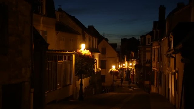 Medieval town at night in France with two people walking
