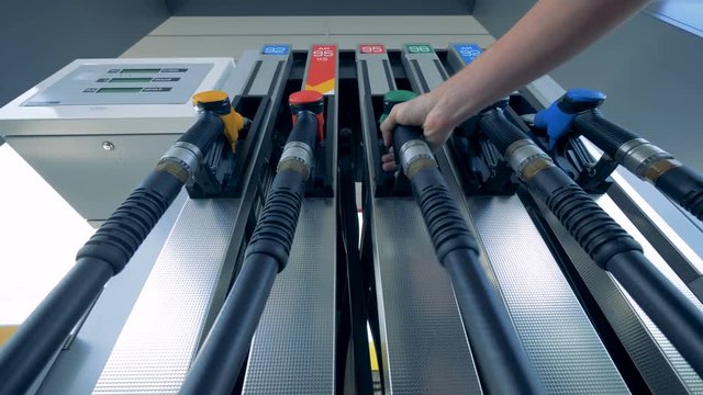 A person holding a petrol nozzle at a filling station, petrol station, fuel station, gasoline station, refueling station.