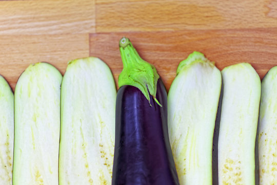 Aubergine or eggplant with slices on wooden background. Close up view.
