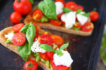 Avocado toast caprese on dark background
