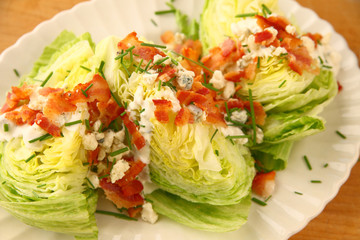 A platter of iceberg lettuce wedges with blue cheese dressing, bacon and chives
