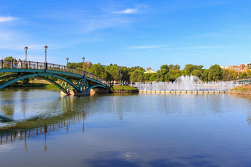 View of bridge to the island Horseshoe and light and music fountain from embankment of Middle Tsaritsynsky pond in Museum-reserve Tsaritsyno in Moscow on a sunny summer morning