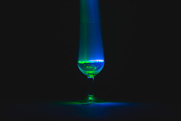 Glass cup full of blue and green light in front of black background