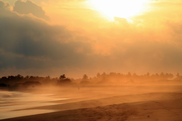 Fototapeta na wymiar Sand Storm over Pacific Ocean Sandy Beach at Sunset.