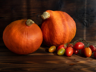 Beautiful pumpkins and cherry tomatoes on dark wooden background