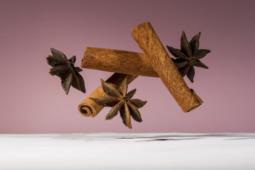 Food levitating, star anise and cinnamon stick levitating on the white wooden table and pink background