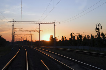 Fototapeta na wymiar Railway tracks going in the direction of a beautiful sunset. The railroad, at sunset.