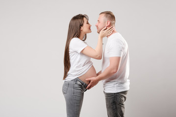 Fototapeta premium Young pregnant woman with husband on white background