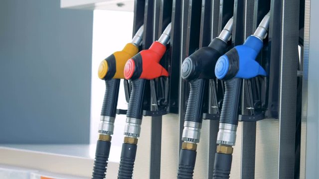 Person takes a nozzle for refilling at a filling station, petrol station, fuel station, gasoline station, refueling station.