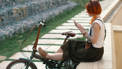 Redhaired woman cyclist making selfie on mobile phone with bike. Woman bicycling