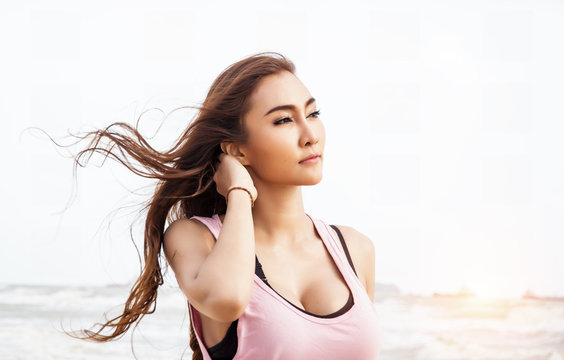 The beauty lady is wearing exercise suit ,raise her right hand touch her neck,portrait lady on the beach
