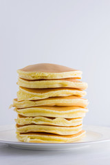 Pancakes on a white background. Many pancakes on a white plate with copy space. Delicious dish for breakfast