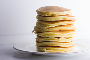 Pancakes on a white background. Many pancakes on a white plate with copy space. Delicious dish for breakfast