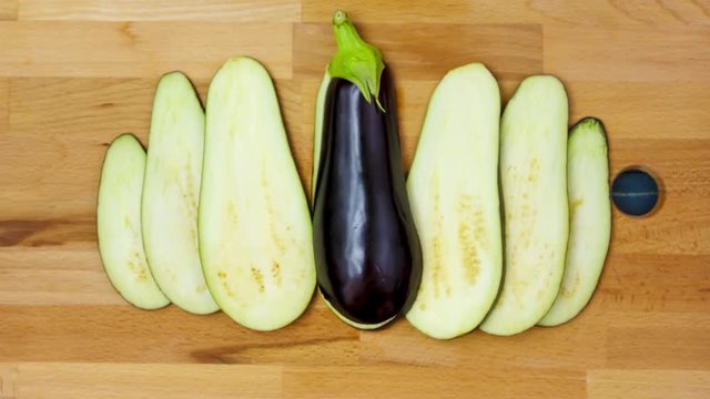 Stop motion of eggplant with slices on wood background. Time lapse of an Aubergine. Close up view