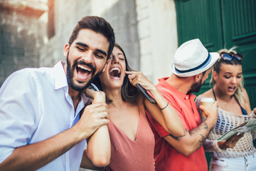 Young happy tourists sightseeing in city. They are having fun listening to music