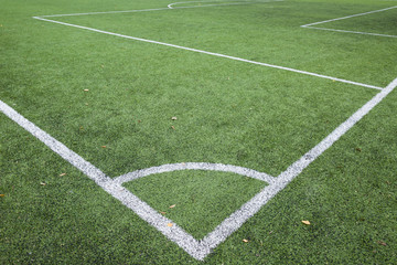 Fototapeta premium Closeup of Football and soccer field corner with white marks, green artificial grass texture in soccer stadium.