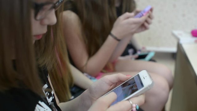 Girls Children with their Smartphones and mobile phone shating in clothes store