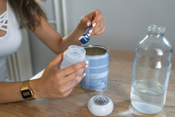 Mother making baby formula in milk bottle