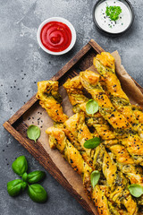 Homemade bread sticks with cheese, pesto sauce and black sesame seeds on gray stone vintage background.  Top view.