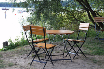 empty wooden table and wooden chairs by the lake