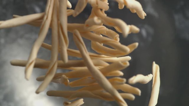 Camera follows throwing riccioli pasta into water. Overhead shot. Shot with high speed camera, phantom flex 4K. Slow Motion.