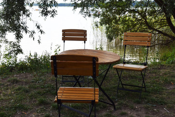 empty wooden table and wooden chairs by the lake