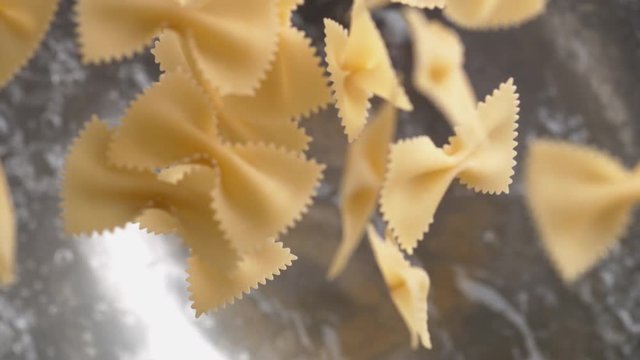 Camera follows throwing farfalle pasta into water. Overhead shot. Shot with high speed camera, phantom flex 4K. Slow Motion.