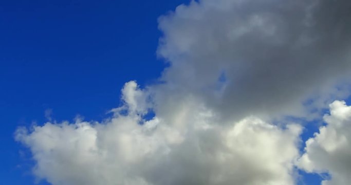 A time lapse film of heavy grey cumulus clouds of a storm front rolling in across a blue sky