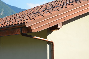 Seitlicher Kupfer-Schutzabschluss eines mit Ziegeln gedeckten Daches mit  Kupfer-Regenrinne und...