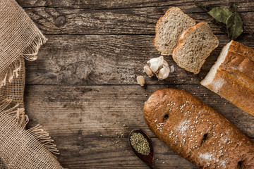 Different fresh bread and spice on rustic wooden background. Creative layout made of bread. Healthy food concept, top view