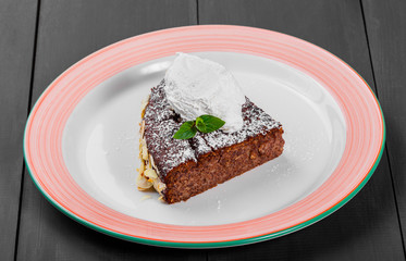 Delicious chocolate cake with almond and vanilla ice cream on plate on dark wooden background, sweet food