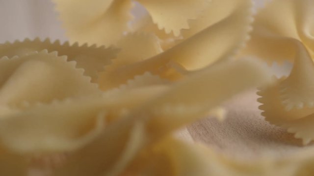 Throwing farfalle ribbon pasta on wooden surface. Shot with high speed camera, phantom flex 4K. Slow Motion.