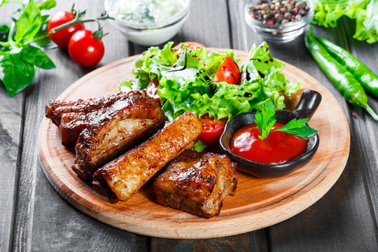Grilled Beef steak with fresh vegetable salad, tomatoes and sauce on wooden cutting board
