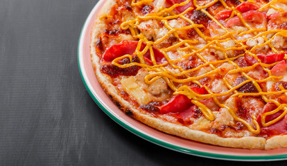 Pizza with chicken, ham, salami, pineapple and mustard on dark wooden background. Homemade pizza. Top view