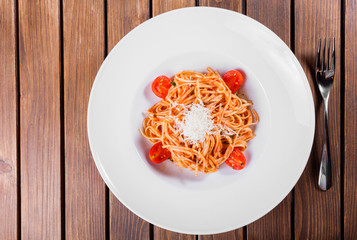 Pasta Spaghetti with olive oil, cheese, herbs and tomatoes on wooden background, Italian cuisine. Ingredients on table
