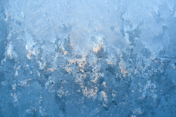 Textured frosty pattern on window lit by winter sun.
