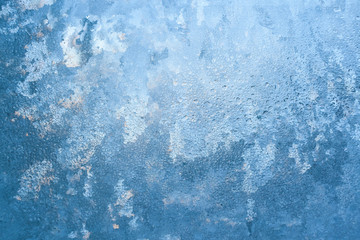 Natural textured frosty pattern on window lit by winter sun as background.