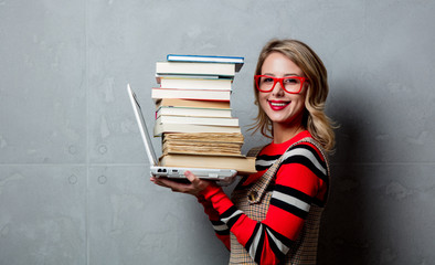 Young girl with laptop computer and books on grey background. Books can be bought via Internet store
