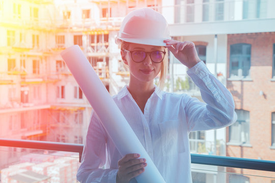 Young engineer woman with helmet and plan on building.