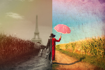 Young girl in coat with suitcase walking along a rural road near cornfield.