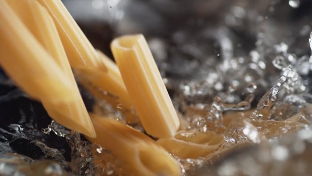 Throwing penne pasta into water. Shot with high speed camera, phantom flex 4K. Slow Motion.