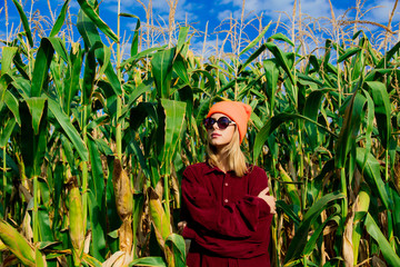 Young girl in sunglasses and shirt in cornfield