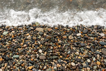waves of the blue sea on a pebble beach. small pebble stones by the sea.
