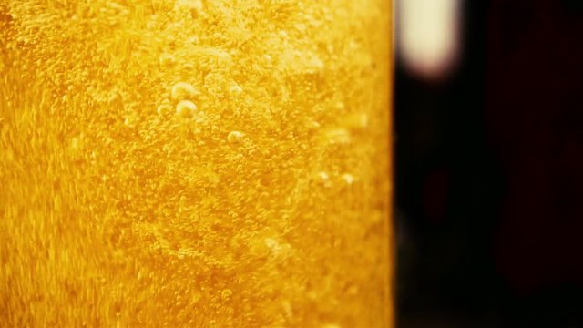 Slow motion a whirl of sparkling bubbles in a clear pour amber drink close-up