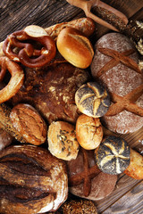 Different kinds of bread and bread rolls on board from above. Kitchen or bakery