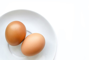 Two chicken eggs in white plate isolated on white background