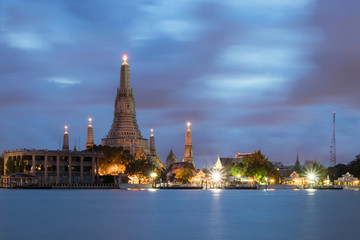 Fototapeta premium Wat Arun Ratchawararam Ratchawaramahawihan or Wat Arun (Temple of Dawn) is a Buddhist temple along the Chao Phraya river at twilight in Bangkok, Thailand. Long exposure