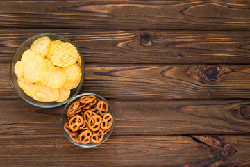 chips, snacks in glass plates on a wooden background. fast food. food for watching TV, competitions. sports matches.