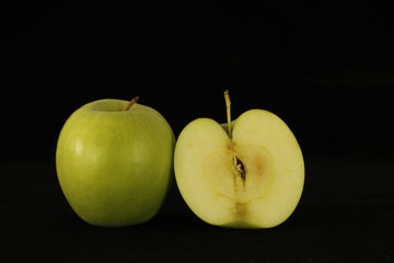 Apple or apples whole or sliced in half on black background.